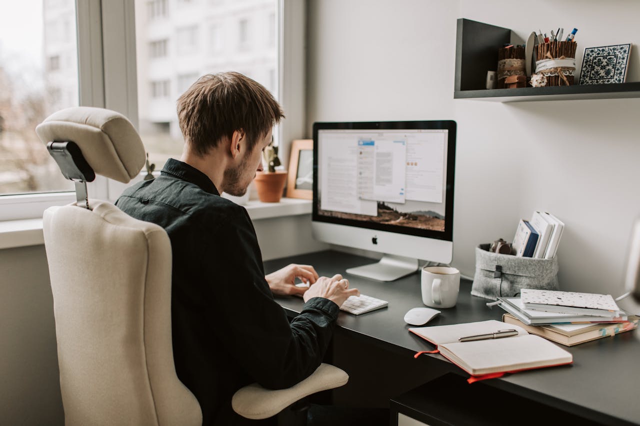 A man in a home office setting working on a computer with a relaxed and focused atmosphere.